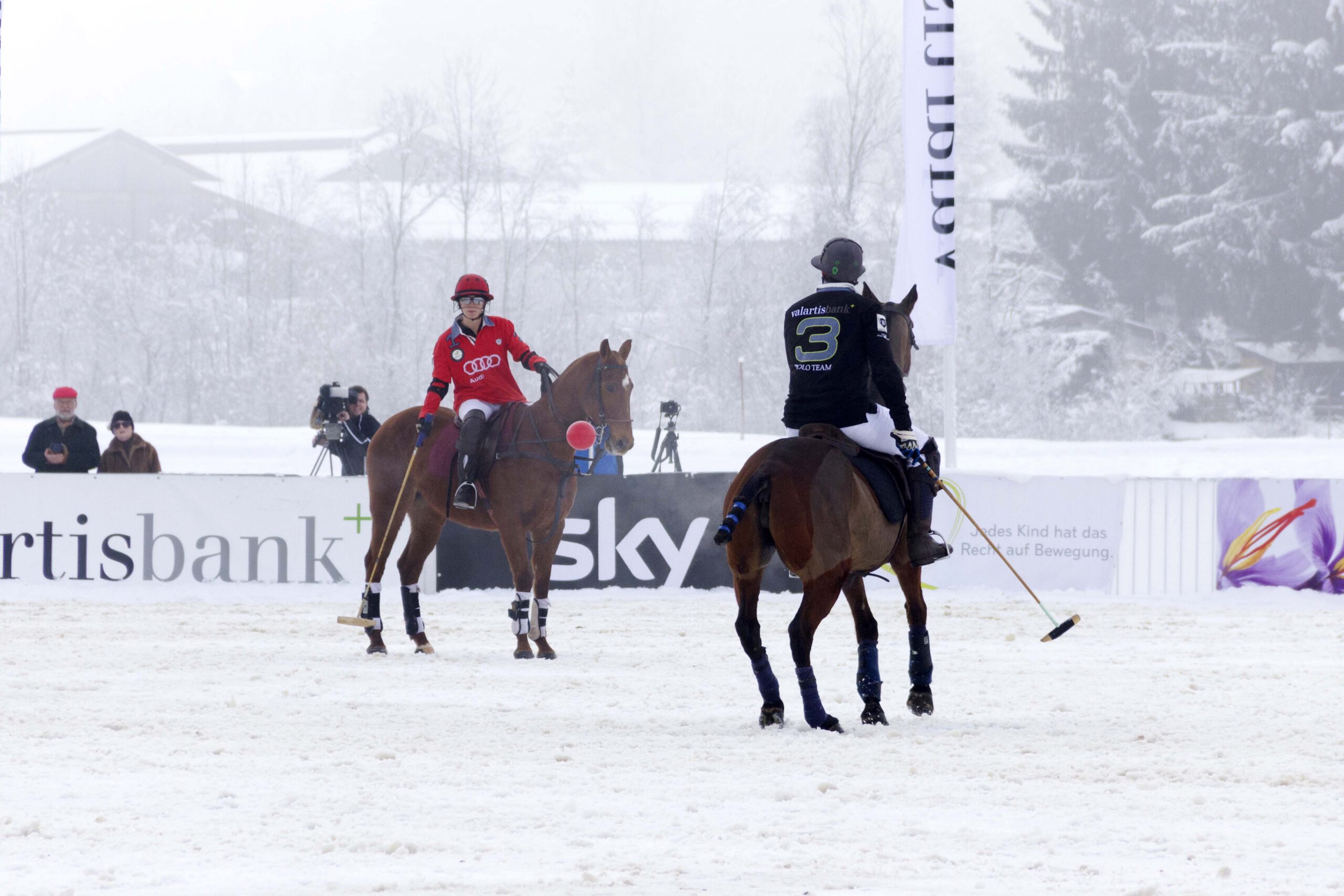 Snow Polo World Cup 2015 mit Polospielern im Schnee und Zuschauern am Spielfeldrand.