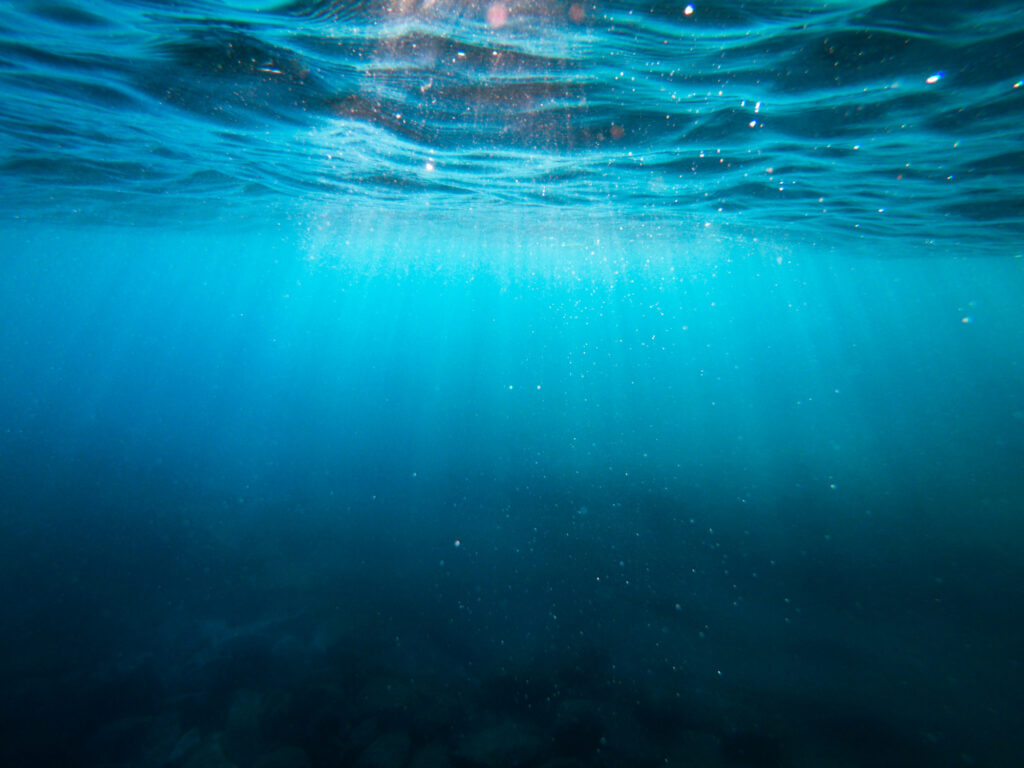 Unterwasser-Visual der Sky Ocean Rescue CSR-Kampagne mit Lichtstrahlen im Meer und weißem Schriftzug zur Förderung von Umwelt- und gesellschaftlicher Verantwortung.
