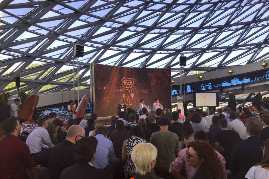 Paneltalk und Community-Event von The Royal Jungle in der BMW Welt München mit über 800 Teilnehmern aus der Startup- und Innovationsszene. Zentrales Element der Bühne war eine Couch aus recycelten PET-Flaschen, auf der Speaker und Gäste während der Talks Platz nahmen. Die Veranstaltung verband Nachhaltigkeit, Community und moderne Markeninszenierung im Umfeld von Sky Ocean Rescue und Startup-Kultur.
